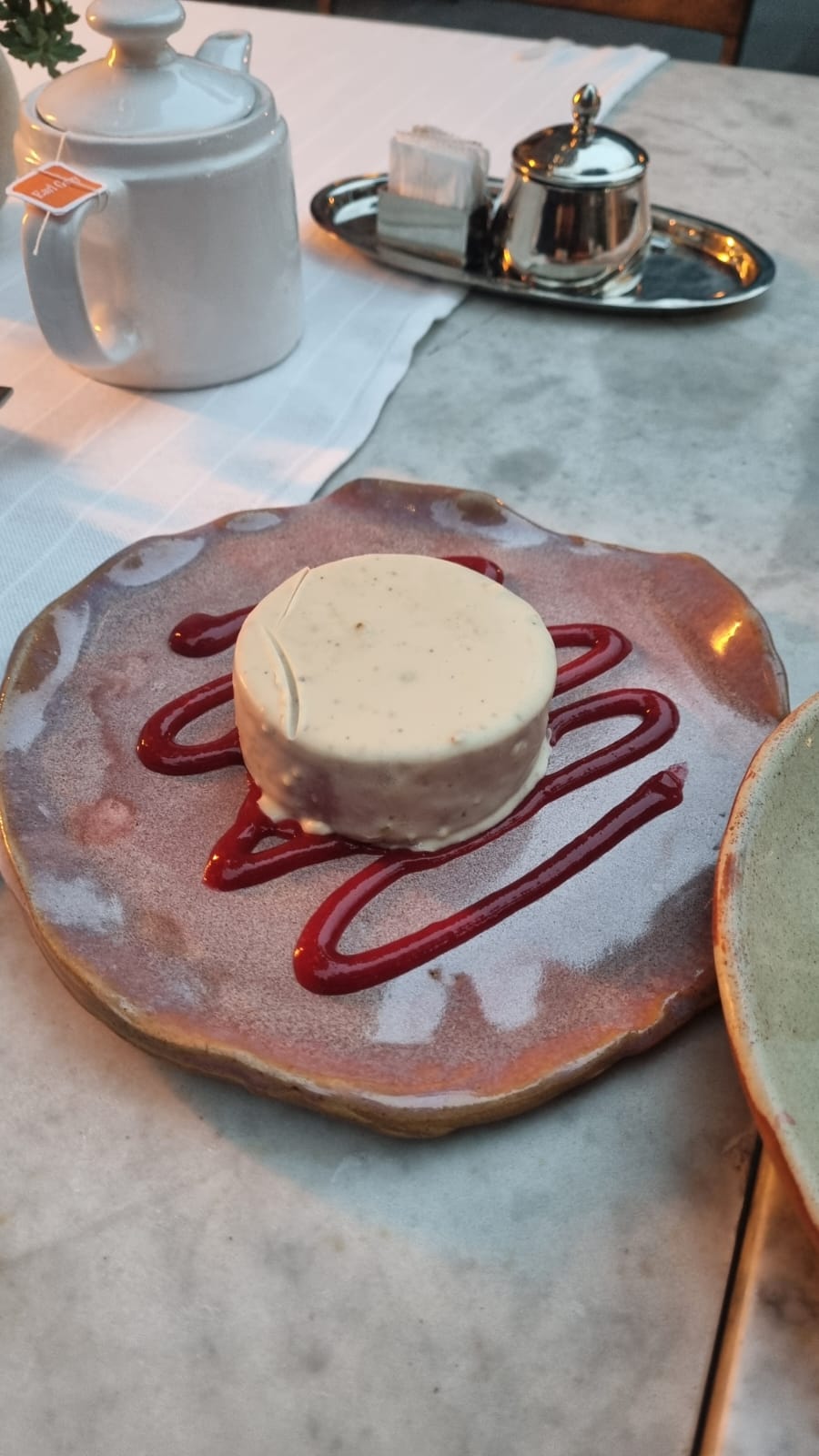 Alfajor de frambuesa, pistacho y chocolate blanco con té de saquito atrás